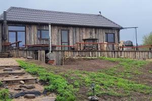 una casa de madera con una valla delante en Ezerdzirnas, 