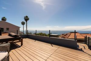 a wooden deck with a view of the ocean at Calheta Tangerine House in Arco da Calheta