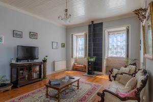 a living room with a couch and a tv at Casa do Hospital-Guest House in Abaças