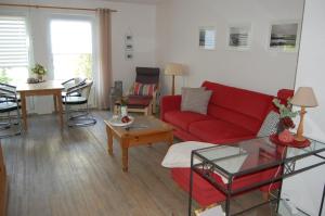 a living room with a red couch and a table at Ferienwohnung Harländer in Petersdorf auf Fehmarn
