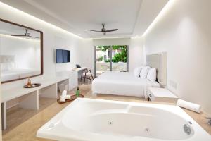 Dormitorio blanco con bañera grande y cama en Antera Hotel & Residences en Playa del Carmen