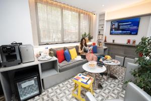 a woman sitting on a couch in a living room at Hôtel Du Mont Dore Batignolles in Paris