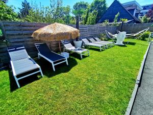 a row of chairs and an umbrella on a lawn at The White Home Broadway Love Room in Châteauroux