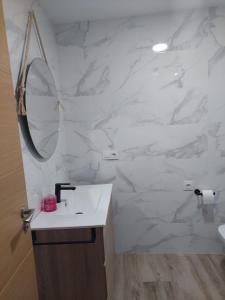 Apartamento en casa Portonovo vacaciones في بورتونوفو: حمام أبيض مع حوض ومرآة