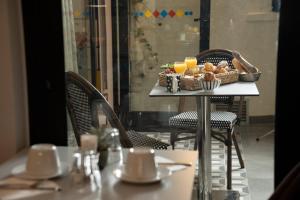 a table with a basket of bread and orange juice at Hôtel Du Mont Dore Batignolles in Paris