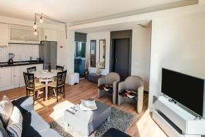 a living room with a couch and a tv and a kitchen at Calheta Tangerine House in Arco da Calheta