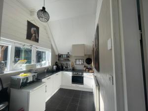uma cozinha com armários brancos e piso em azulejo preto em Vakantiehuis Het Uilennest em Wijdenes