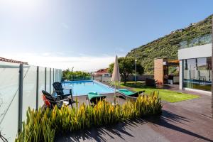 a house with a swimming pool and two chairs at Calheta Tangerine House in Arco da Calheta