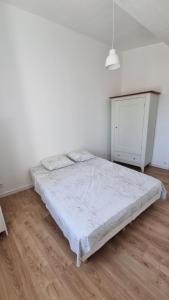 a white bedroom with a bed and a wooden floor at En plein coeur de Pélissanne - 55 m2 rénovés - Avec Parking in Pélissanne