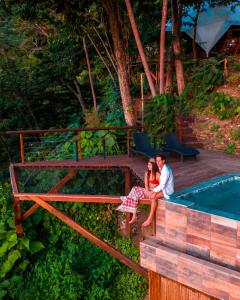 a man and woman sitting on a bench next to a swimming pool at Trekker Glamping in Minca