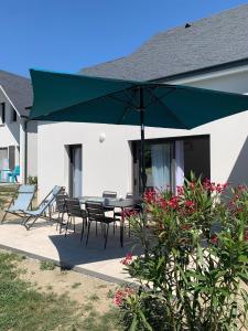 a patio with a table and chairs and a green umbrella at Gite les edelweiss Fleurs des Pyrénées in Argelès-Gazost