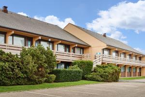 a building with bushes in front of a parking lot at Kyriad Direct Le Havre Est - Gonfreville in Gonfreville-lʼOrcher