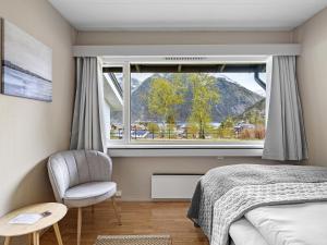 Eidfjord Hotel في إيدفيورد: غرفة نوم مع نافذة وكرسي وسرير