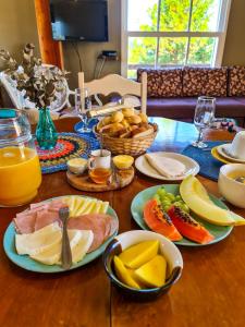 a wooden table topped with plates of food and fruit at Villas da Bocaina in Bananal