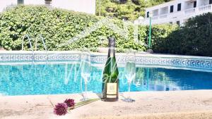 uma garrafa de vinho ao lado de uma piscina em VILLA LORENZo em Cala Blanca