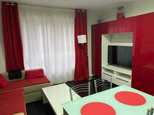 un soggiorno con tende rosse e TV di Apartamento de playa familiar, piscina y garaje. a Ares