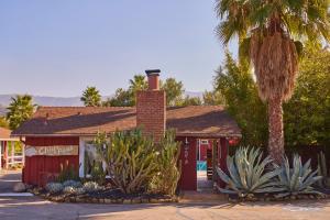 a red building with a palm tree in front of it at Ojai Rancho Inn in Ojai