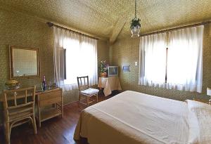 a bedroom with a bed and a desk and two windows at Hotel Maestoso in Montecatini Terme