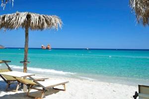 uma praia com duas cadeiras e um guarda-sol e o oceano em La Stella Marina em Bari Sardo