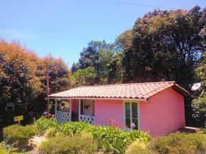 a small pink house with a red roof at Hospedaje Santaelena -chalets de montaña- in Santa Elena