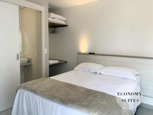 um quarto com uma cama com lençóis brancos e almofadas em Pousada BRAWAY em Curitiba