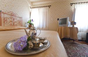 モンテカティーニ・テルメにあるHotel Maestosoのベッドの上にトレイ(お茶ポット、花付)