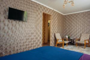 a bedroom with a bed and a tv on a wall at 1-комнатная квартира в центре на Аль-Фараби 93 in Kostanay