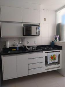 een keuken met witte kasten en een magnetron bij Apto Lindo Agua in Campos dos Goytacazes