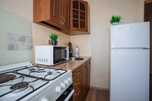 a kitchen with a stove and a white refrigerator at 1-комнатная квартира в центре на Аль-Фараби 93 in Kostanay