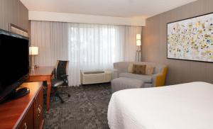 a hotel room with a bed and a desk and a television at Courtyard by Marriott Newark Silicon Valley in Newark