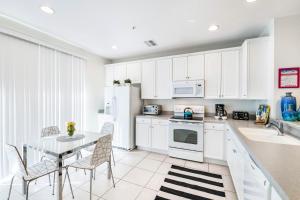 uma cozinha com armários brancos e uma mesa e cadeiras em Beautiful Newly Updated Townhome Sleeps 10 em Orlando