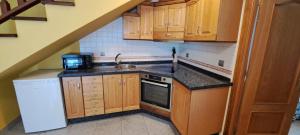 a small kitchen with wooden cabinets and a sink at Llanes-Llumedian in Llanes
