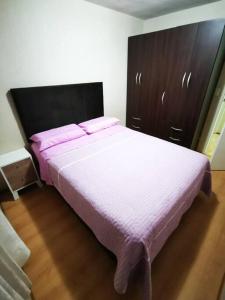 a bedroom with a large bed with pink sheets at Hermoso departamento en condominio in Tacna