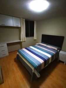 1 dormitorio con 1 cama con manta azul y blanca en Hermoso departamento en condominio en Tacna