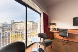 a room with a large window with a desk and chairs at Leonardo Hotel Utrecht City Center in Utrecht