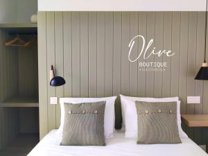 a bed with white sheets and pillows with a wine boutique sign at Olive Boutique Guesthouse in Vila Franca do Campo