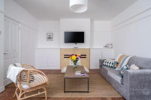 Bright West Hampstead Retreat في لندن: غرفة معيشة مع أريكة و إناء من الزهور