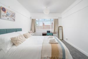 Bright West Hampstead Retreat في لندن: غرفة نوم بيضاء مع سرير كبير ومكتب