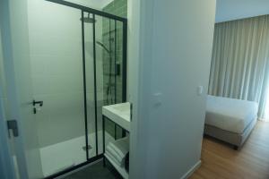 a bathroom with a glass shower and a bed at Olive Boutique Guesthouse in Vila Franca do Campo