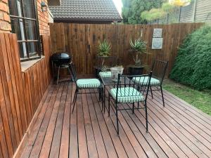 a patio with four chairs and a table on a deck at Greenwood Lea Cottage - luxury, romantic cottage in Hilton