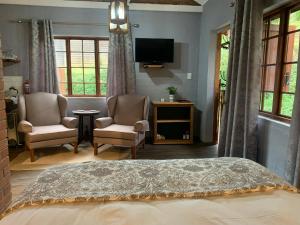 a bedroom with a bed and two chairs and a television at Greenwood Lea Cottage - luxury, romantic cottage in Hilton