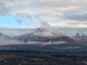 een met sneeuw bedekte berg in het midden van een veld bij Advie Lodge in Inverness