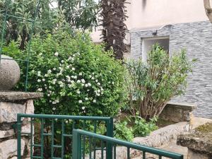 a green fence in front of a bush with white flowers at Apartman Nika in Crikvenica