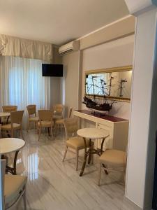una habitación con mesas y sillas y un barco en un espejo en Hotel Amica, en Rímini