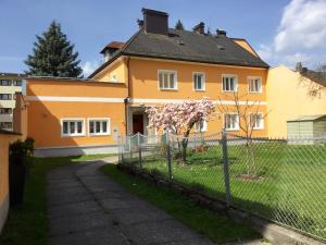 uma casa amarela com uma cerca em frente em Salzburgrooms em Salzburgo