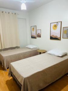 two beds in a room with paintings on the wall at Apartamento centro de Guarapari in Guarapari