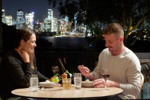 a man and a woman sitting at a table with wine glasses at Roar And Snore in Sydney