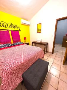 a bedroom with a bed with a pink and yellow wall at Sofia Hostel Cabo in Cabo San Lucas