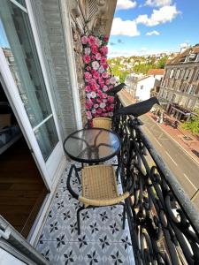 uma varanda com duas cadeiras, uma mesa e flores em L'Etoile Imani -Amazing apartment near Orly Airport em Villeneuve-Saint-Georges
