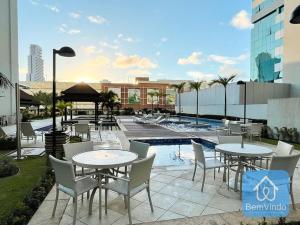 a patio with tables and chairs next to a pool at Apartamento ao lado do Salvador Shopping 4 in Salvador